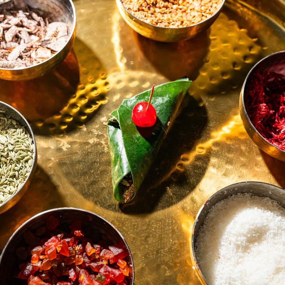 A Tikkaville paan with a cherry on top, surrounded by bowls of colorful ingredients.